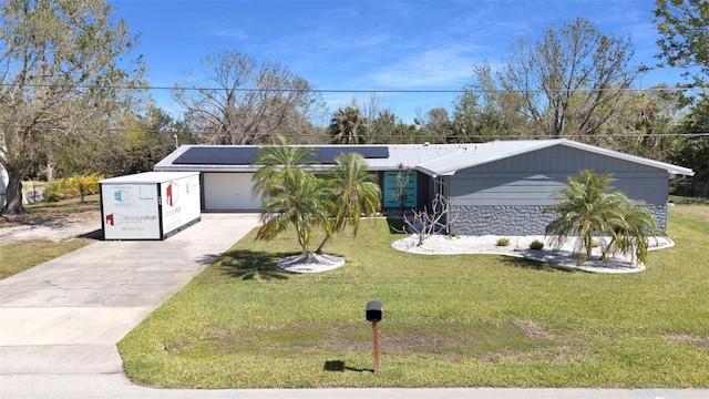 view of front of home featuring a garage, concrete driveway, a front yard, and roof mounted solar panels