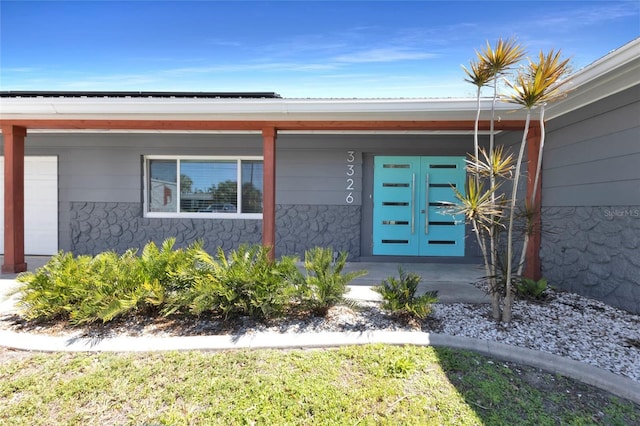 doorway to property with an attached garage, covered porch, and roof mounted solar panels