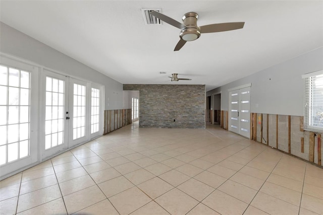 unfurnished living room with a ceiling fan, a wainscoted wall, light tile patterned flooring, and visible vents