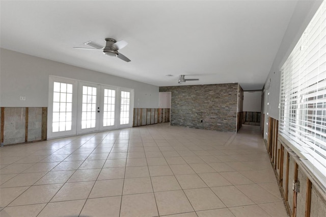 unfurnished living room featuring a wainscoted wall, ceiling fan, and light tile patterned flooring