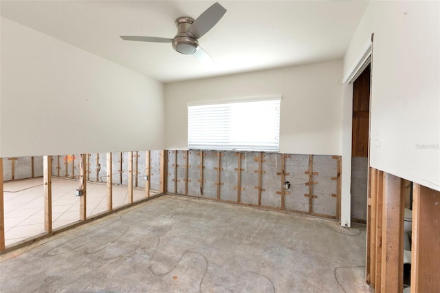 unfurnished room with ceiling fan and unfinished concrete flooring