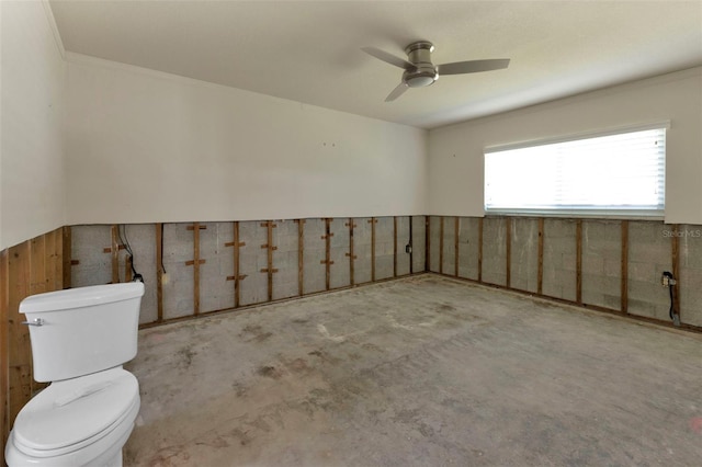 interior space with concrete floors, wainscoting, and a ceiling fan