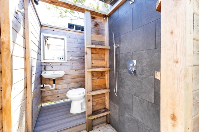 bathroom featuring tiled shower, a sink, and toilet