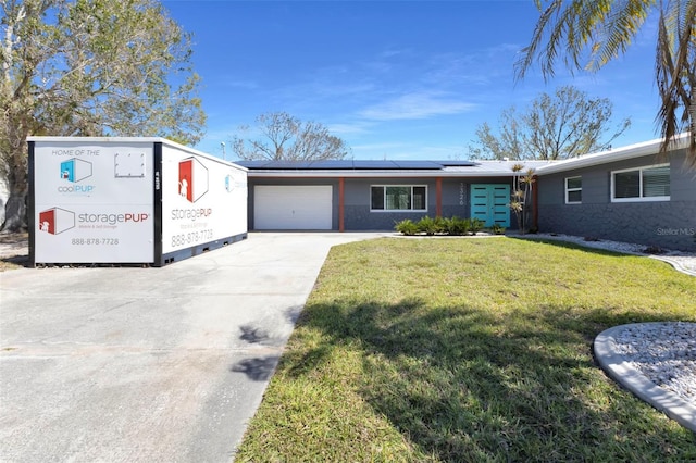 view of front of home featuring an attached garage, driveway, a front yard, and roof mounted solar panels