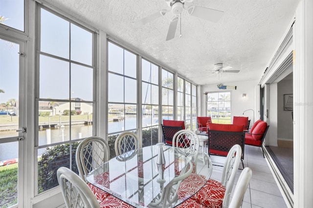 sunroom featuring a water view and a ceiling fan