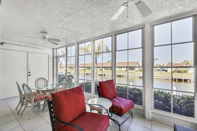 sunroom featuring a water view and a ceiling fan