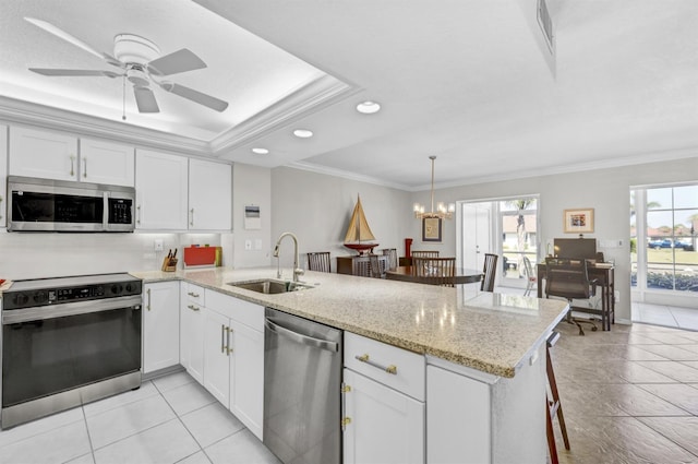 kitchen featuring appliances with stainless steel finishes, a peninsula, crown molding, white cabinetry, and a sink