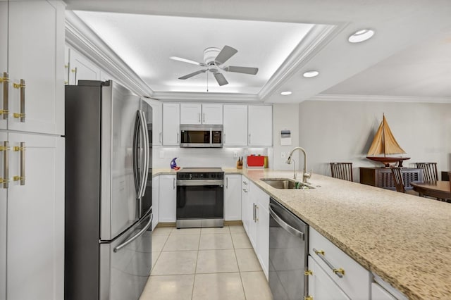 kitchen featuring crown molding, a raised ceiling, appliances with stainless steel finishes, light tile patterned flooring, and a sink