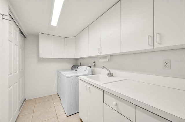 laundry room featuring light tile patterned floors, a sink, baseboards, independent washer and dryer, and cabinet space