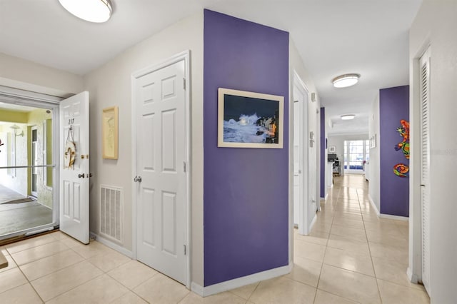 hall with visible vents, baseboards, and light tile patterned floors