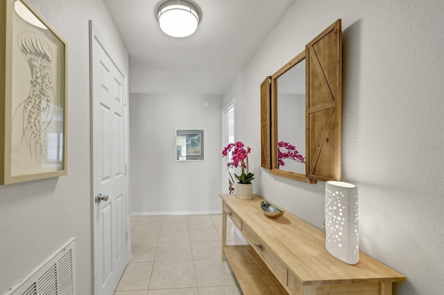 hallway with baseboards, visible vents, and light tile patterned flooring