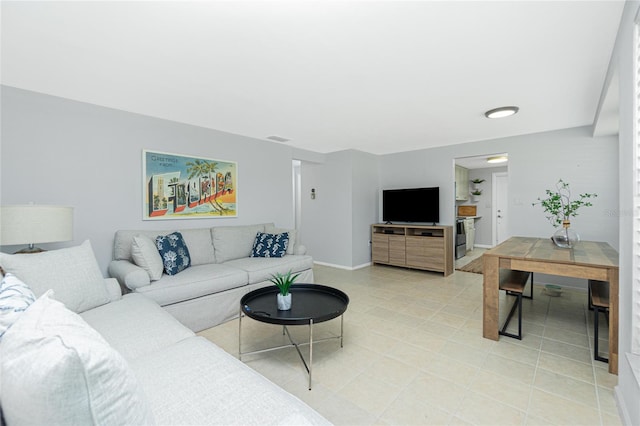 living room with light tile patterned floors, visible vents, and baseboards