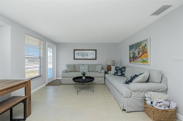 living area featuring light tile patterned floors, visible vents, and baseboards