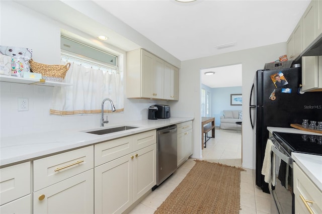 kitchen featuring light tile patterned floors, appliances with stainless steel finishes, a sink, light countertops, and backsplash