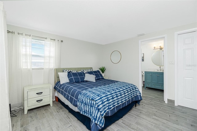 bedroom with a sink, connected bathroom, visible vents, and light wood-style floors