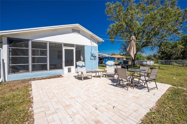 view of patio featuring a sunroom, fence, and outdoor dining area