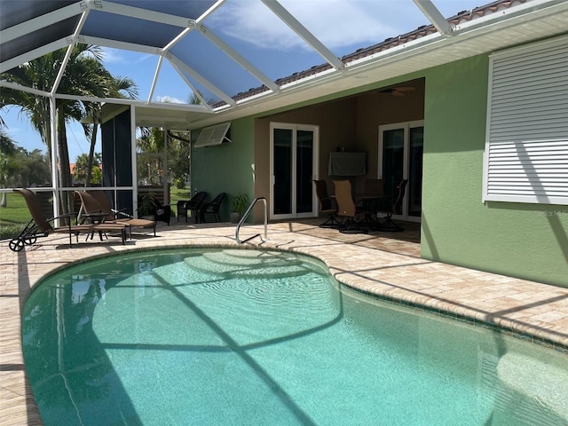 outdoor pool featuring a patio, glass enclosure, a wall mounted air conditioner, and a ceiling fan