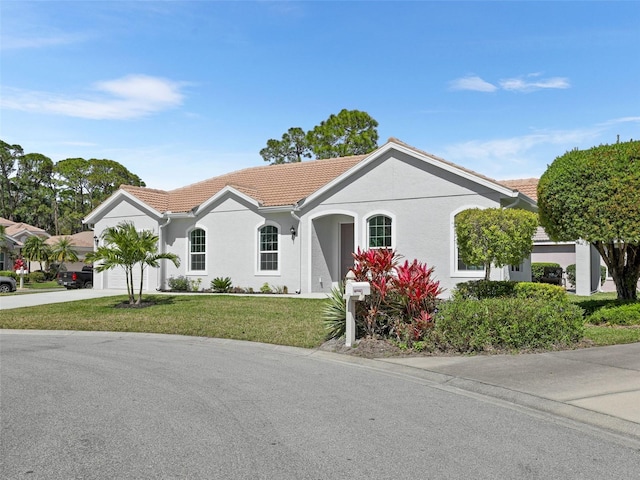 view of front of home featuring a garage, a tiled roof, driveway, stucco siding, and a front lawn