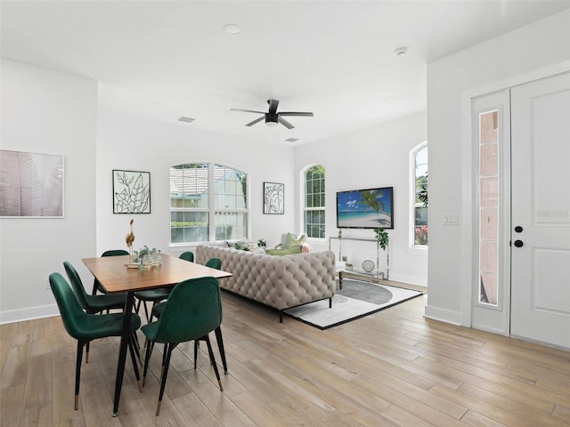 dining space featuring light wood finished floors, baseboards, visible vents, and ceiling fan