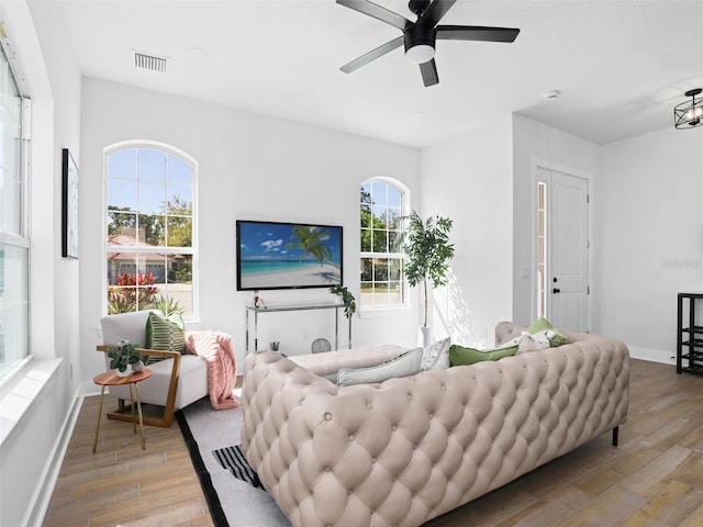 living area featuring baseboards, visible vents, ceiling fan, and light wood finished floors