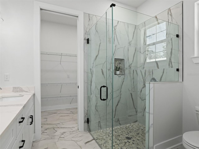 bathroom with a marble finish shower, marble finish floor, toilet, and a spacious closet