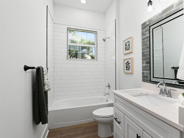 bathroom featuring toilet, wood tiled floor, vanity, and shower / bathing tub combination