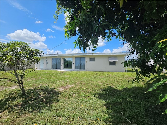 rear view of property featuring a yard and stucco siding