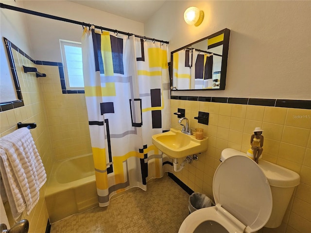 full bath with tile walls, toilet, a wainscoted wall, shower / bath combination with curtain, and a sink