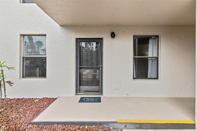 doorway to property featuring stucco siding