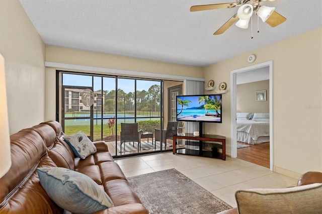 living room with tile patterned floors, baseboards, a textured ceiling, and ceiling fan