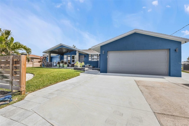 view of front facade with an attached garage, a front yard, concrete driveway, and stucco siding