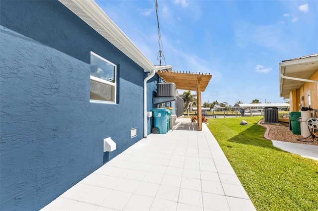 view of side of property featuring a patio, stucco siding, a lawn, central AC, and a pergola