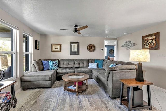 living area featuring ceiling fan, baseboards, and light tile patterned floors