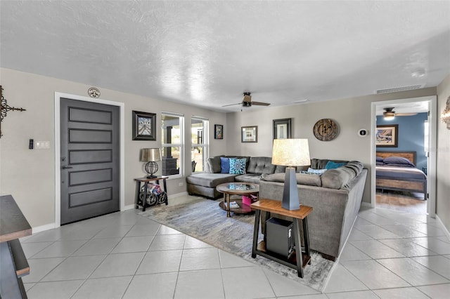 living room featuring a ceiling fan, visible vents, a textured ceiling, and light tile patterned floors