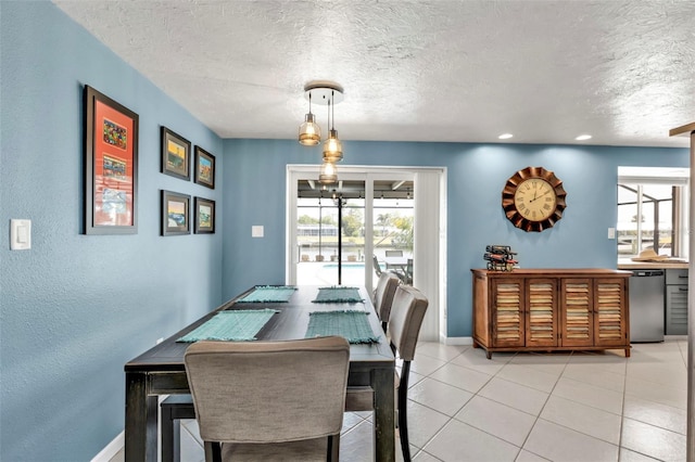 dining area featuring a wealth of natural light, light tile patterned flooring, a textured ceiling, and baseboards