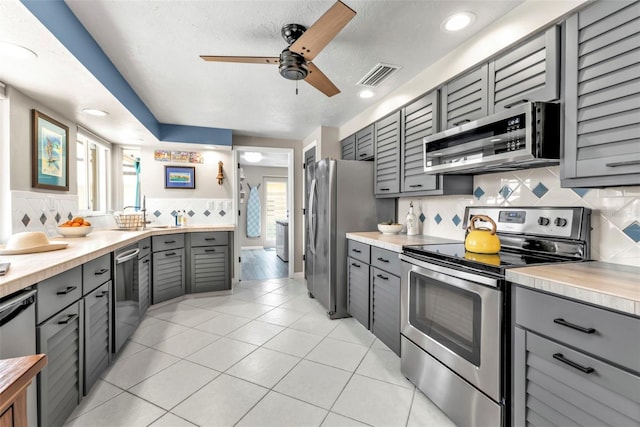 kitchen with stainless steel appliances, light countertops, visible vents, and gray cabinetry