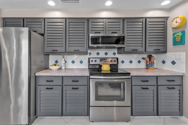 kitchen featuring tasteful backsplash, stainless steel appliances, gray cabinets, and light countertops