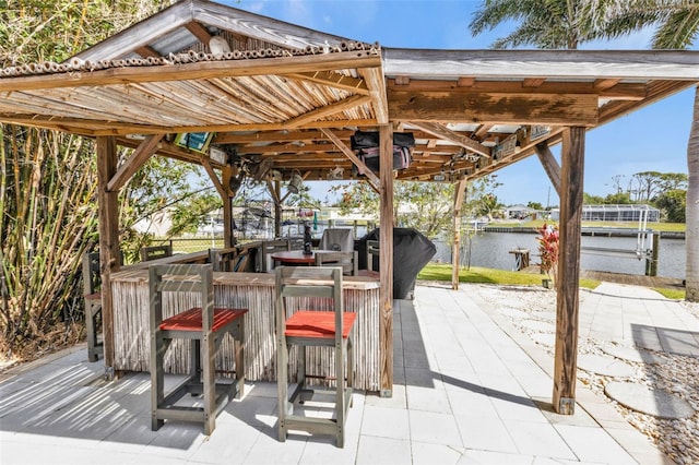 view of patio / terrace with a water view, a boat dock, outdoor dry bar, and boat lift