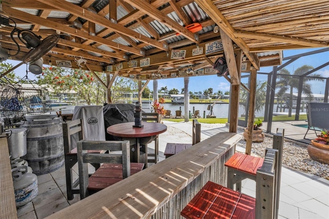 view of patio featuring a water view and glass enclosure