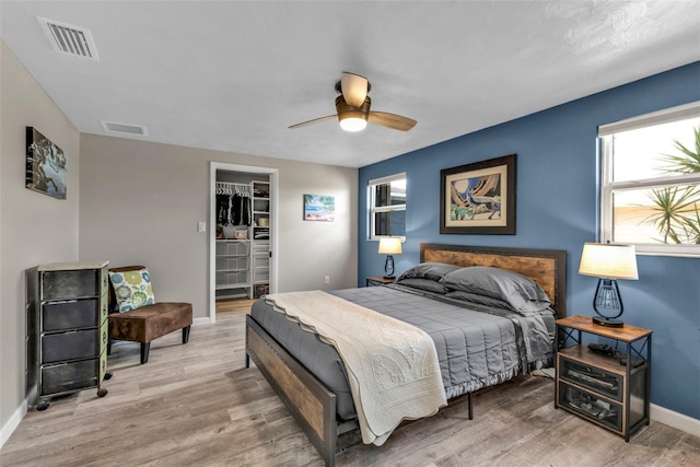 bedroom featuring light wood-type flooring, a walk in closet, and visible vents