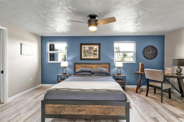 bedroom with light wood-type flooring, multiple windows, and baseboards