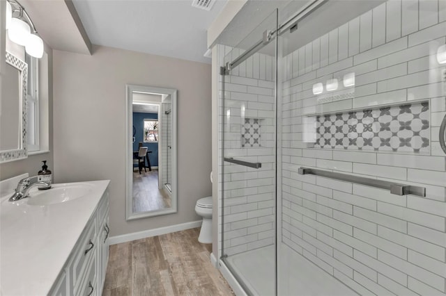 bathroom with a stall shower, vanity, toilet, and wood finished floors