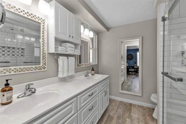 full bathroom with double vanity, wood finished floors, a stall shower, and a sink