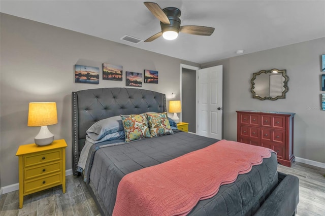 bedroom with a ceiling fan, baseboards, visible vents, and wood finished floors