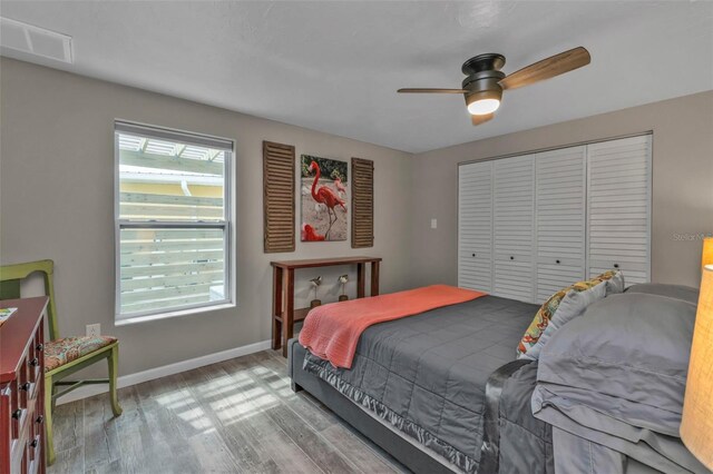 bedroom with a closet, wood finished floors, visible vents, and baseboards