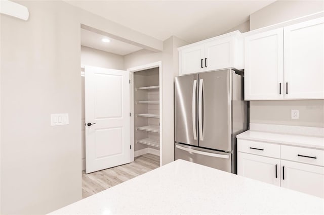 kitchen featuring light wood finished floors, freestanding refrigerator, and white cabinets