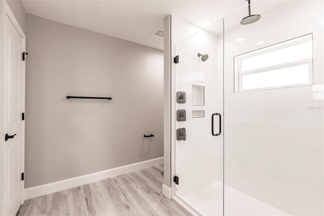 bathroom featuring a stall shower, visible vents, baseboards, and wood finished floors