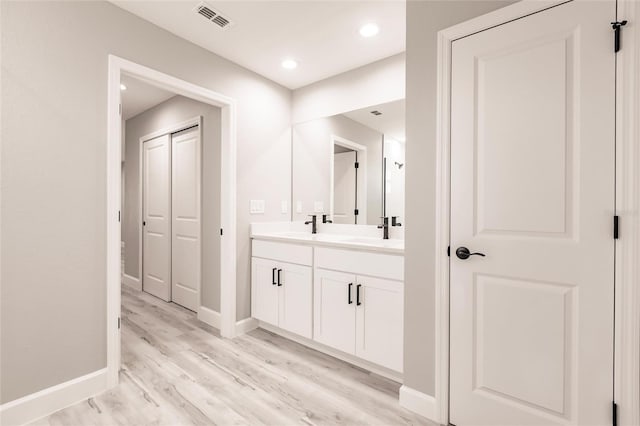 bathroom featuring recessed lighting, wood finished floors, visible vents, baseboards, and double vanity