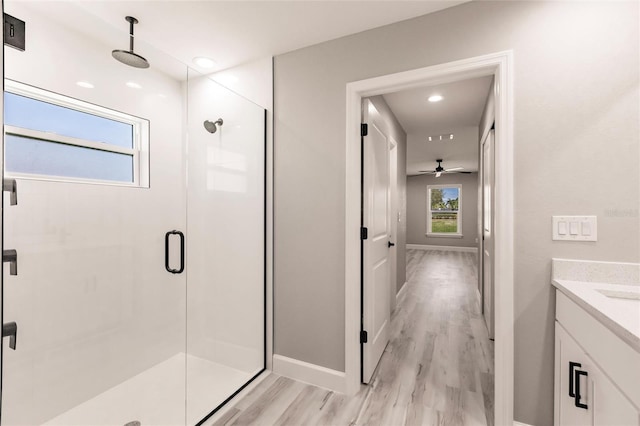 bathroom featuring a shower stall, baseboards, wood finished floors, and vanity