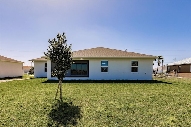 back of property with fence, a lawn, and stucco siding